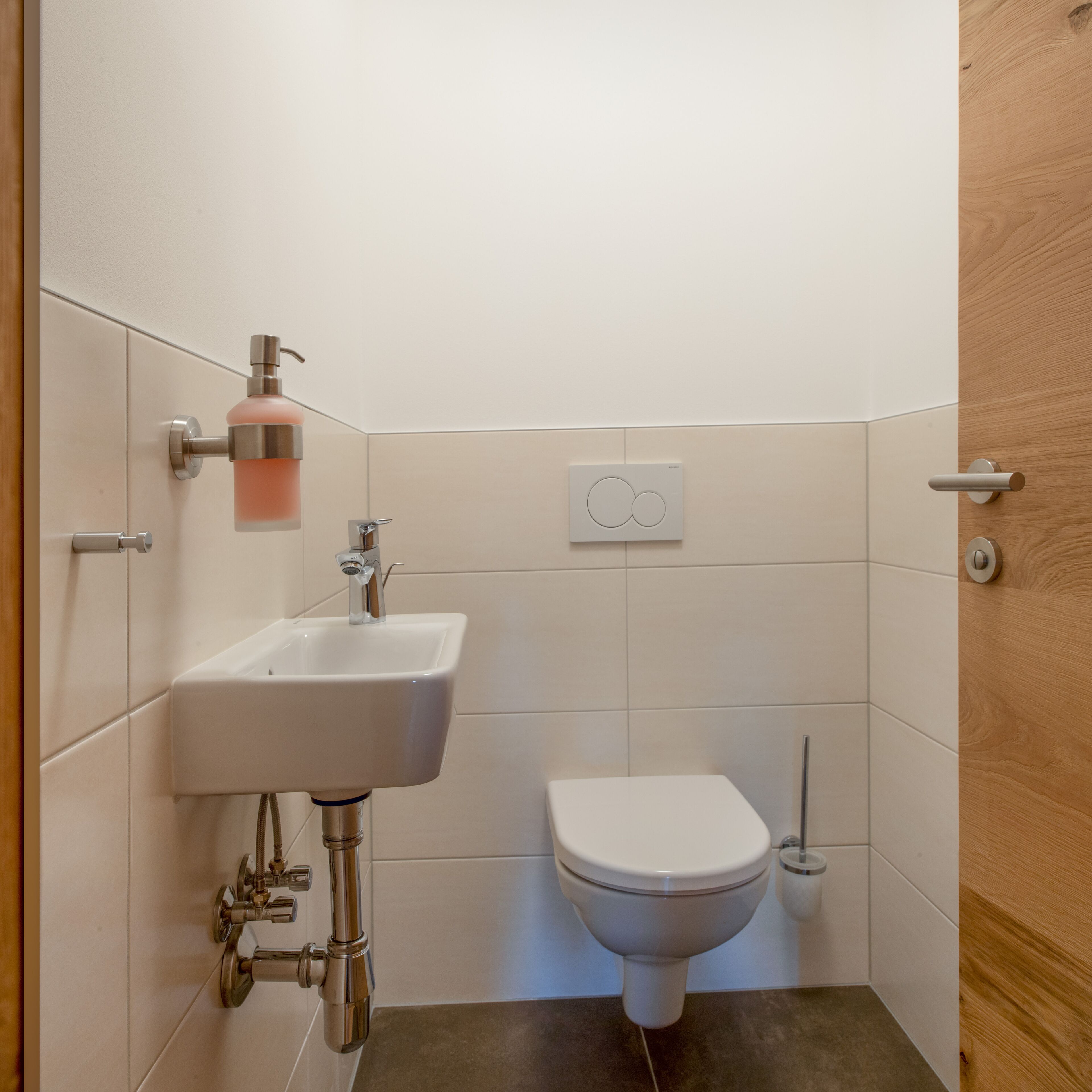 A bathroom with a white sink, a toilet, and a wooden door.