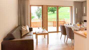 Ein modernes Wohnzimmer mit einer braunen Ledersofa, einem Holztisch und einem Essbereich mit Holztisch und Stühlen.