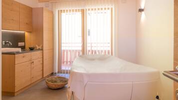 A modern bathroom with a bathtub, wooden cabinets, and a window with blinds.
