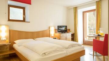 A hotel room with a wooden bed, a television, a desk with a computer, and a red chair.