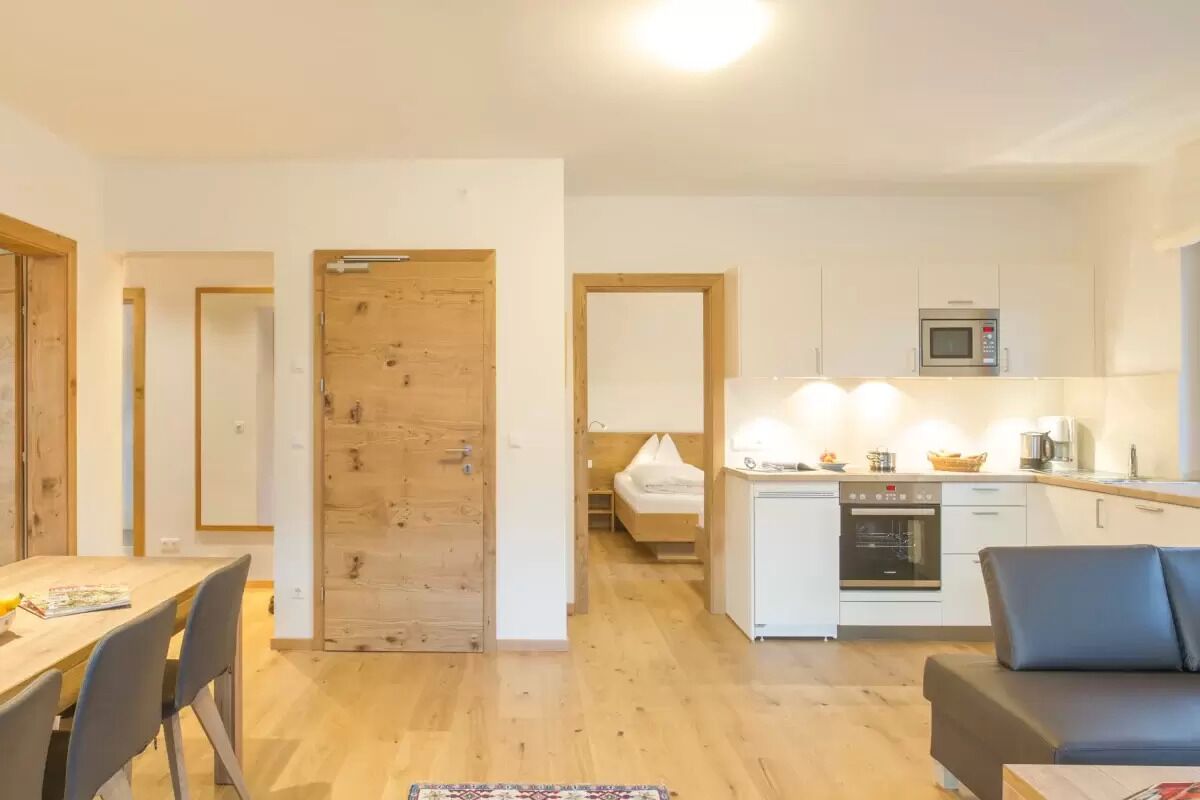 A compact living space with a dining area, kitchenette, and a small bedroom.