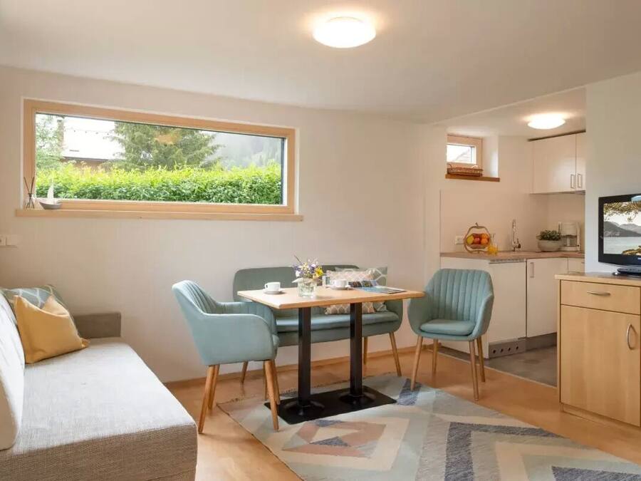 A compact living space with a sofa, a dining table with chairs, a TV, and a kitchen area.