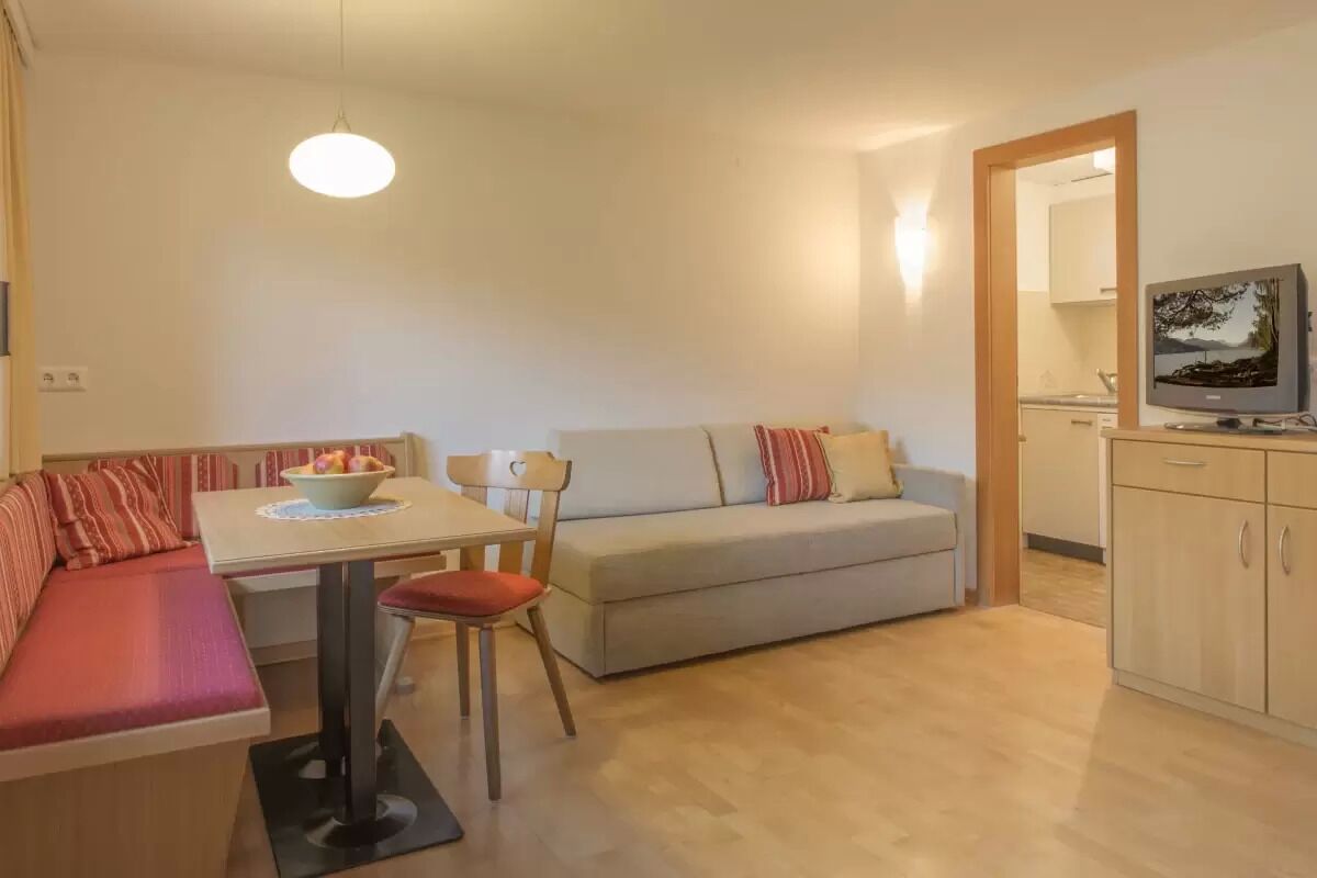 Un espacio habitable compacto con una mesa de comedor, un sofá, un televisor y un armario.