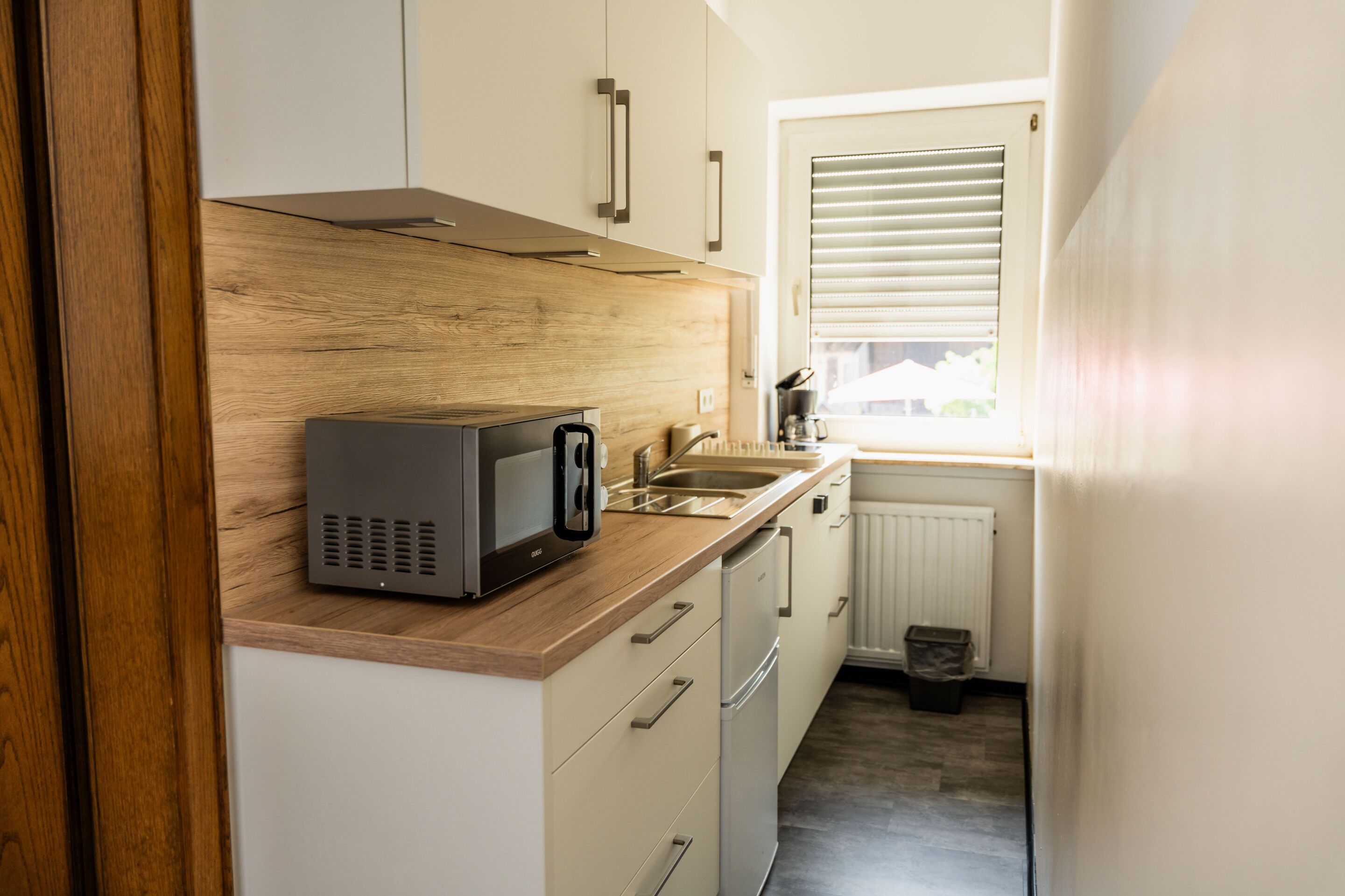 A compact kitchen with a microwave, sink, and wooden countertop.