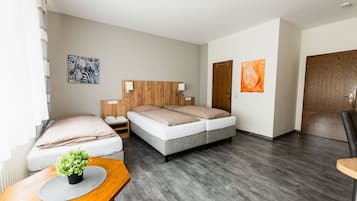 Ein modernes Hotelzimmer mit einem großen Bett, Nachttischen, einem hölzernen Kopfteil und zwei Bildern an den Wänden.
