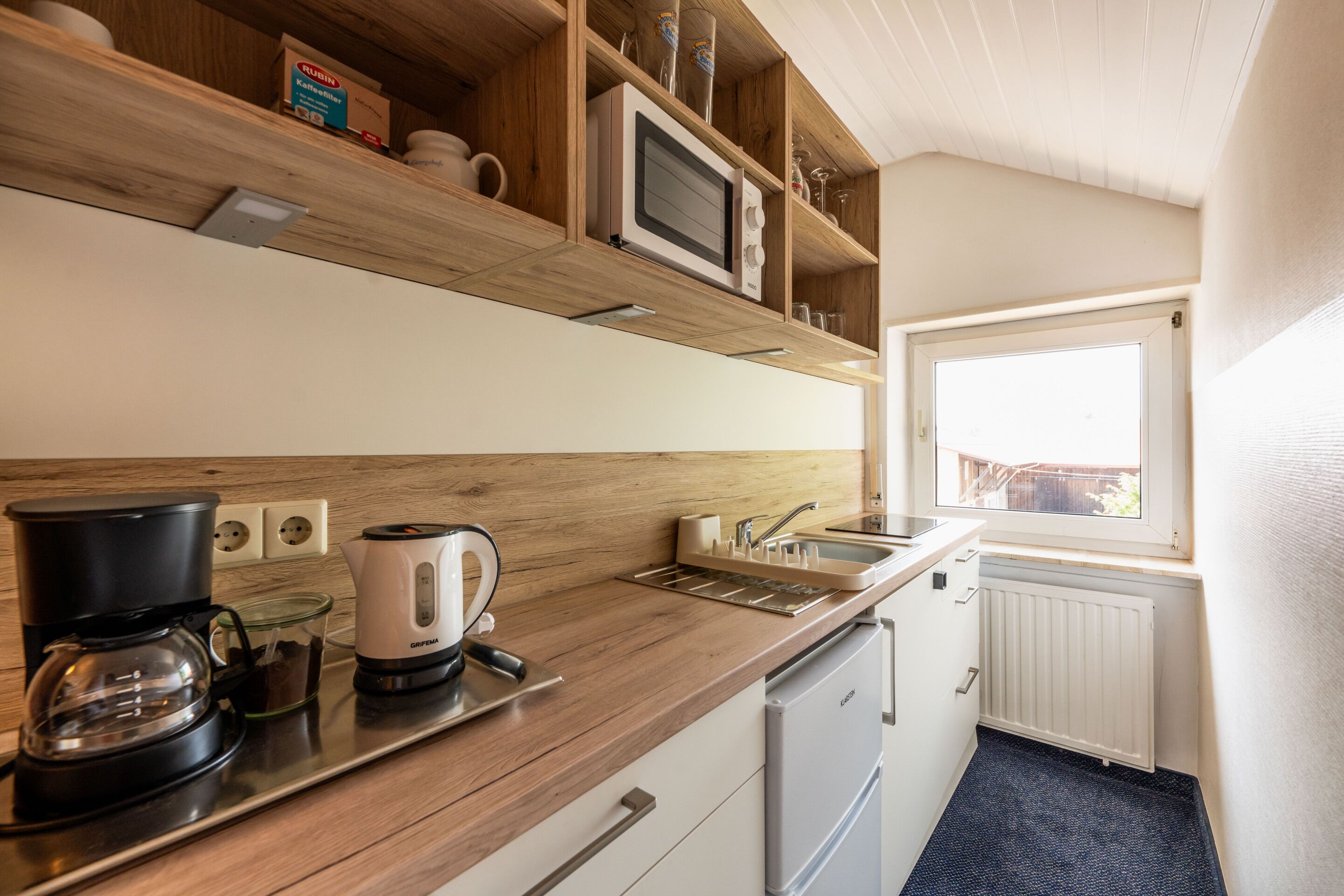 Una cocina compacta equipada con microondas, cafetera y lavavajillas.