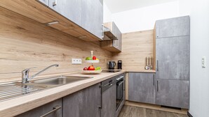 A modern kitchen with a wooden countertop, stainless steel sink, and grey cabinets. - Landhotel Georgshof (Huenfeld)