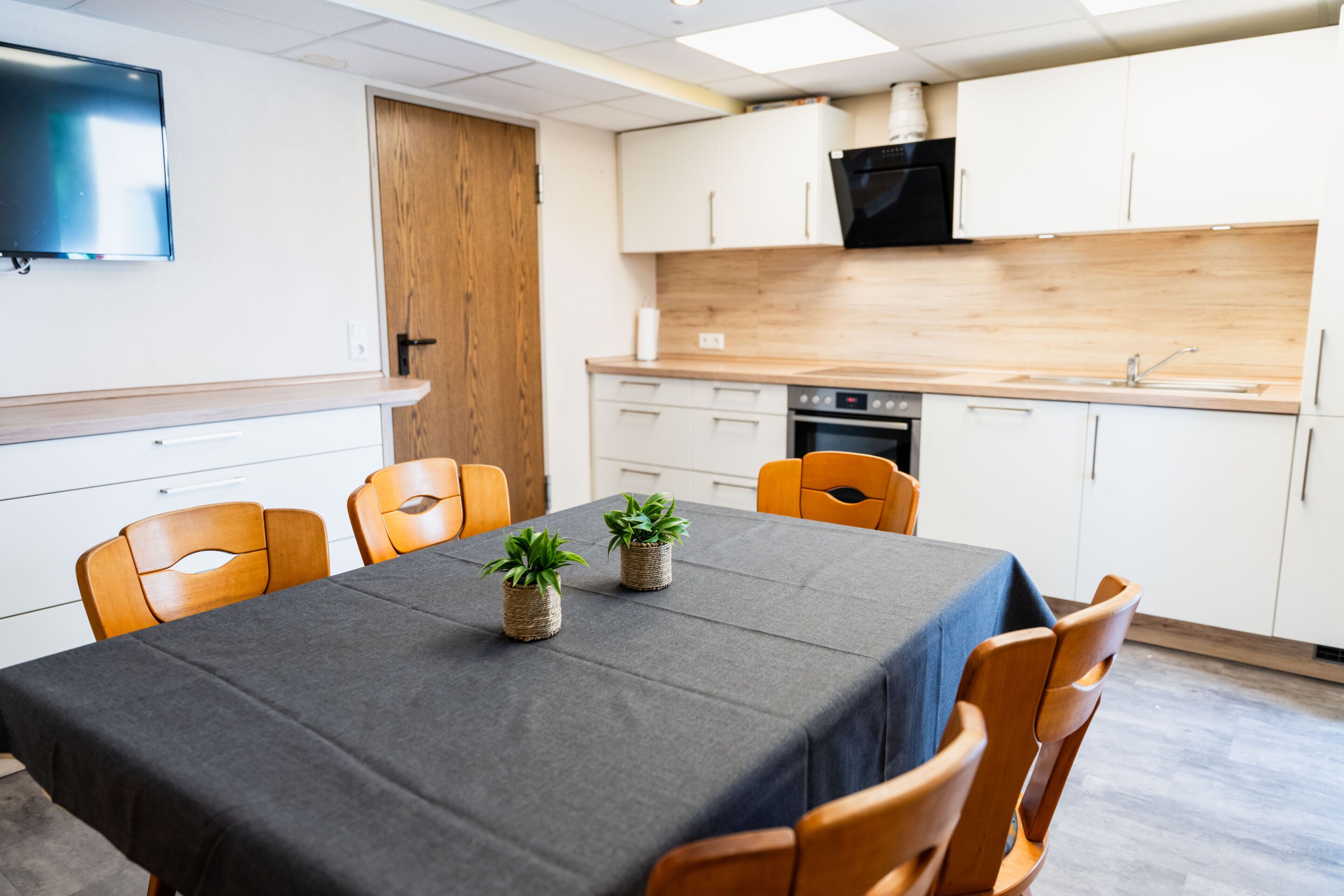 A modern kitchen with white cabinets, a black oven, and a wooden countertop.