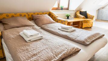 Habitación de hotel moderna con dos camas individuales, una pequeña mesa, una silla y un ventanal con vistas.
