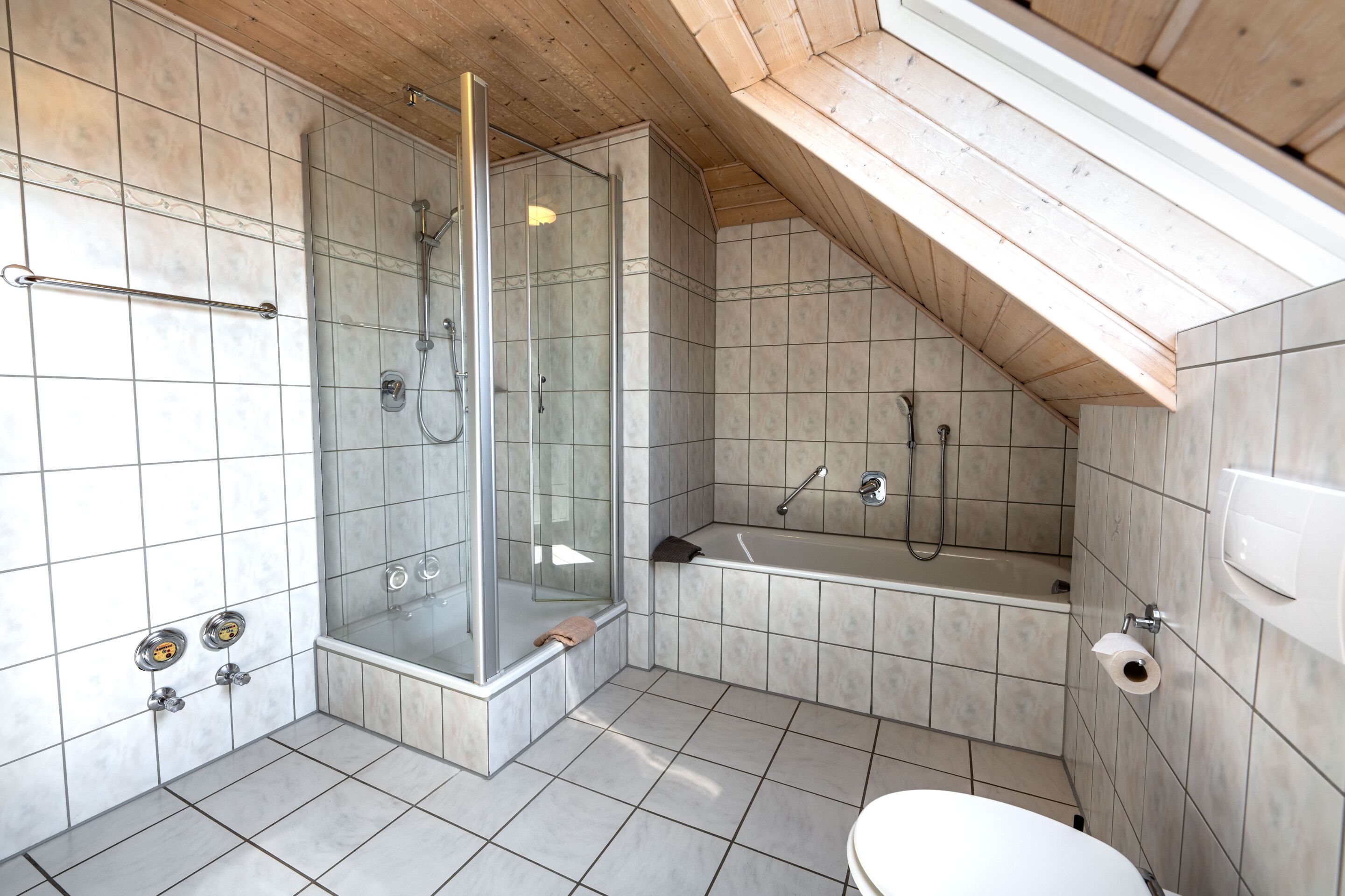 Un baño moderno con cabina de ducha de vidrio, bañera y retrete.