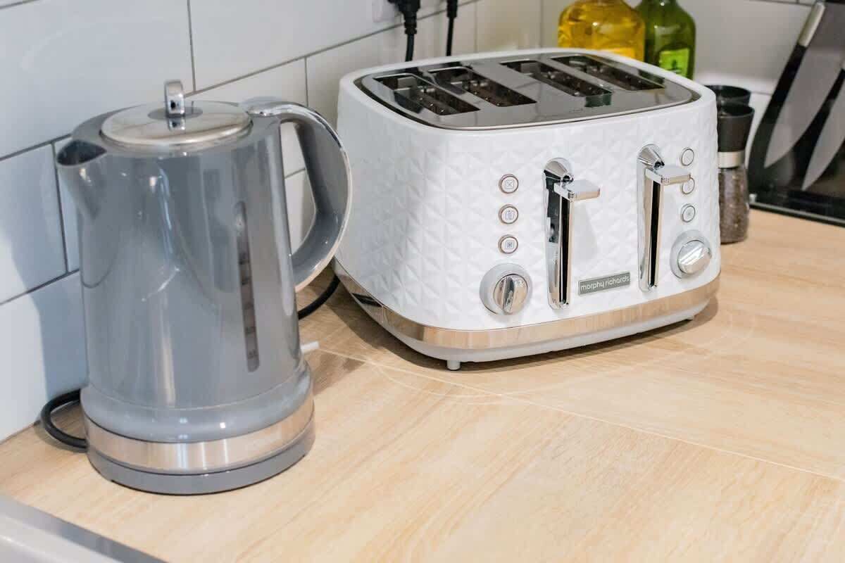 A kitchen with a white toaster and a gray electric kettle on a wooden countertop.
