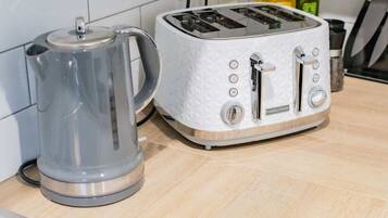 A kitchen with a white toaster and a gray electric kettle on a wooden countertop.