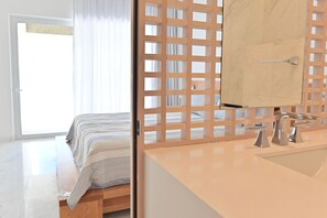 Ein modernes Schlafzimmer mit Bett, einer Holzwand und einem Badezimmer mit Waschbecken und Spiegel.