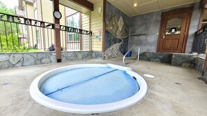A swimming pool with a stone wall and a wooden door. - Open Plan Living Area, 2 Q Beds, Full Kitchen, Walk to Trails, Portable AC (Fernie)
