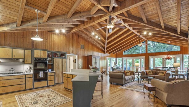 Une cuisine spacieuse avec des meubles en bois, un îlot central et une grande fenêtre donnant sur une forêt.