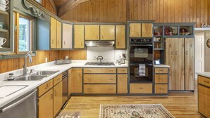 Une cuisine avec des meubles de rangement en bois, un évier en acier inoxydable, une cuisinière et un four.