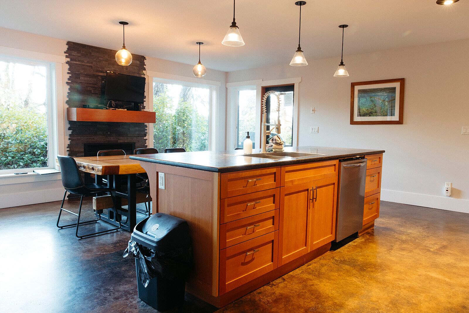 Een moderne keuken met een groot kookeiland, houten kastjes en hanglampen.