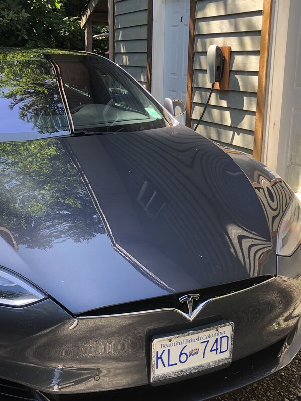 Une voiture noire était garée devant une maison dont la porte et le portail du garage étaient en bois.