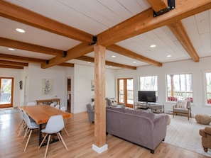 Relax in this spacious living area with a high ceiling, comfortable sofa, and large dining table.