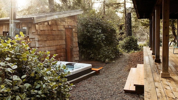 A wooden deck with a hot tub, surrounded by gravel and greenery. - Cozy home in Tofino w/ hottub (Tofino)