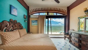 Ein Schlafzimmer mit Bett, Schminktisch und Blick auf den Strand.