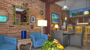 Ein Zimmer mit Backsteinwand, blauen Sofas, Korbmöbeln und einer farbenfrohen, vogelartigen Vase.