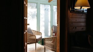 Una habitación con sillas de mimbre, una lámpara y vistas a través de un ventanal.