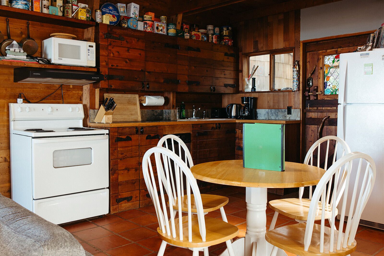 A kitchen with wooden cabinets, a stove, a microwave, and a dining table with chairs.