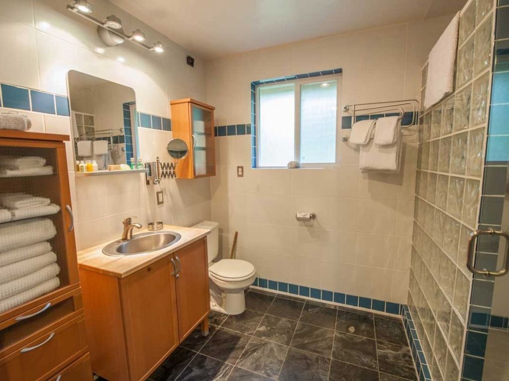 A bathroom with a sink, mirror, cabinet, toilet, and a shower area.