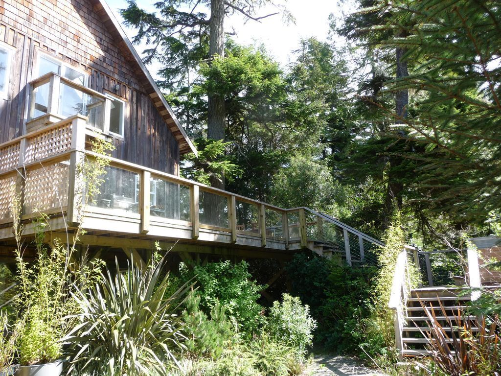 A wooden cabin with a deck and a staircase leading to a covered area.