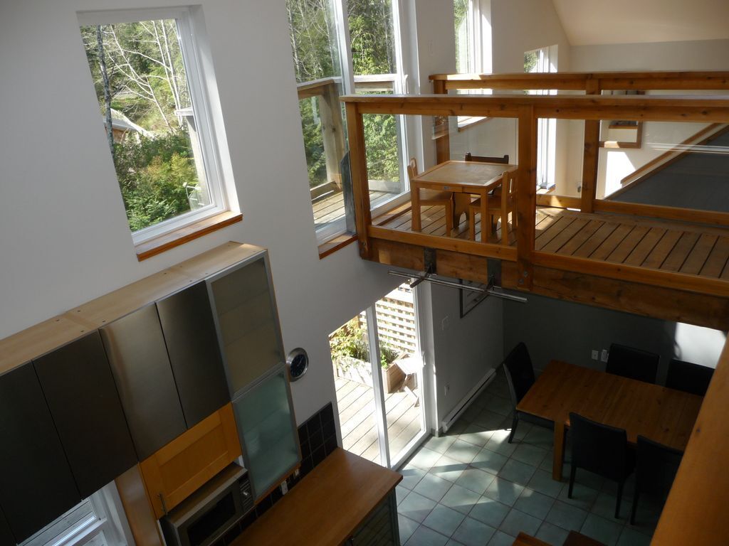 A loft-style room with a wooden mezzanine, a dining area, and a view of the outdoors.