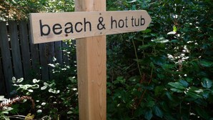 A wooden sign with the text "beach & hot tub". - The Yacht House, Tofino B.C. (Tofino)