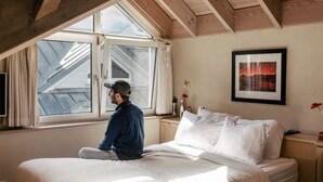 A room with a bed, a window, a framed picture, and a wooden ceiling. - The Yacht House, Tofino B.C. (Tofino)