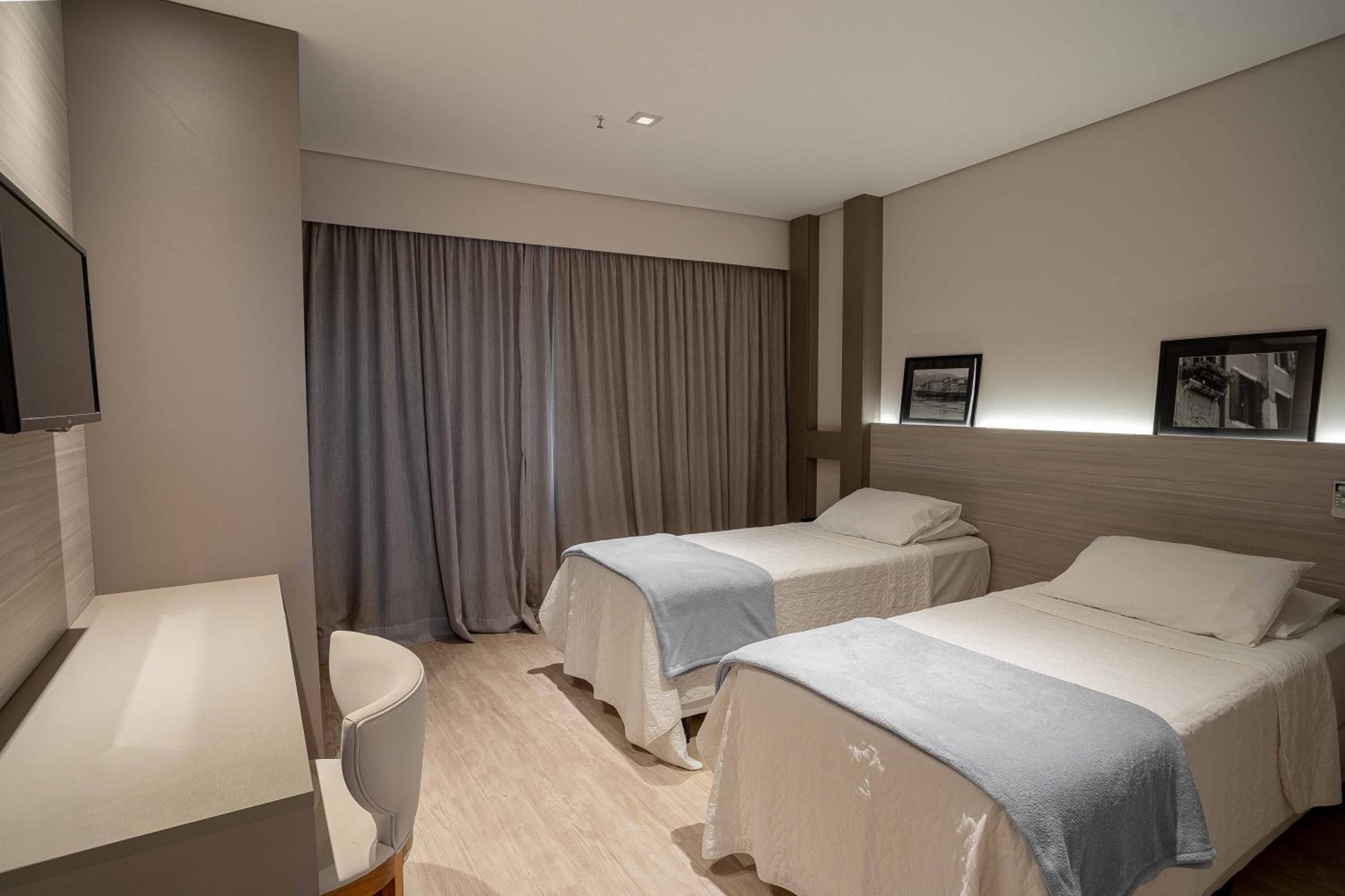 Habitación de hotel con dos camas, un escritorio y un televisor.