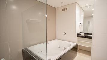 A modern bathroom with a glass-enclosed shower, a large bathtub, and a vanity with a black countertop.