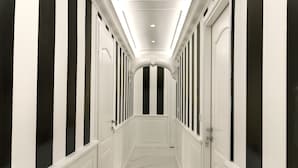 Um corredor comprido e estreito, com paredes brancas e listras verticais pretas.