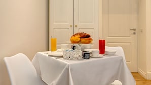 Mesa de café da manhã posta com croissants, suco e uma cafeteira.