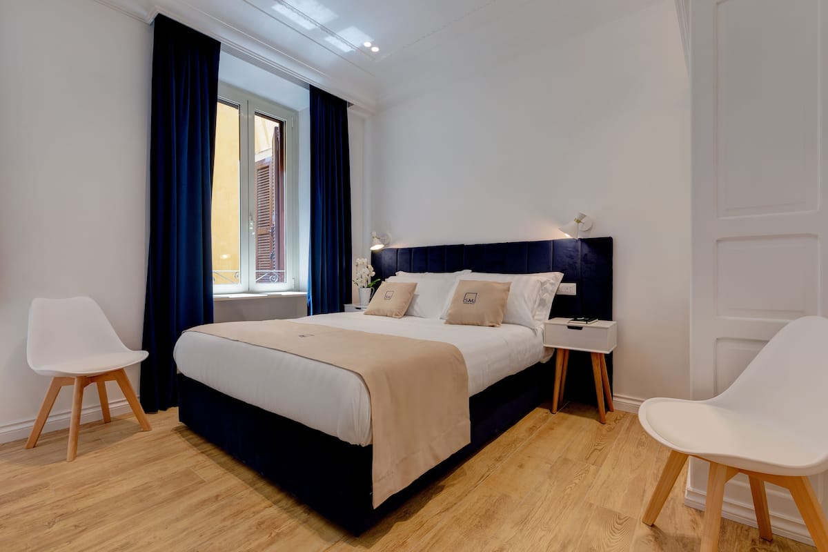 A modern bedroom with a bed, bedside tables, and chairs.