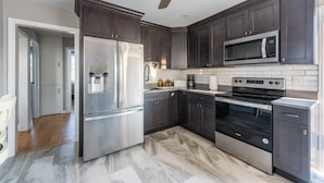 A modern kitchen with dark cabinets, stainless steel appliances, and a marble floor. - 2026 LAVALLETTE NEW Kitchen and Bathroom, Outdoor Shower & BEACH BADGES INCLUDED (Lavallette)