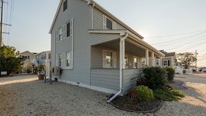 A two-story house with a covered porch, a gravel driveway, and a small garden area. - 2026 LAVALLETTE NEW Kitchen and Bathroom, Outdoor Shower & BEACH BADGES INCLUDED (Lavallette)