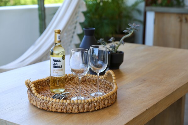 A bottle of wine, two glasses, and a woven tray on a wooden table. - Mi Lugar Stylish couple getaway rooftop/pool (Sayulita)