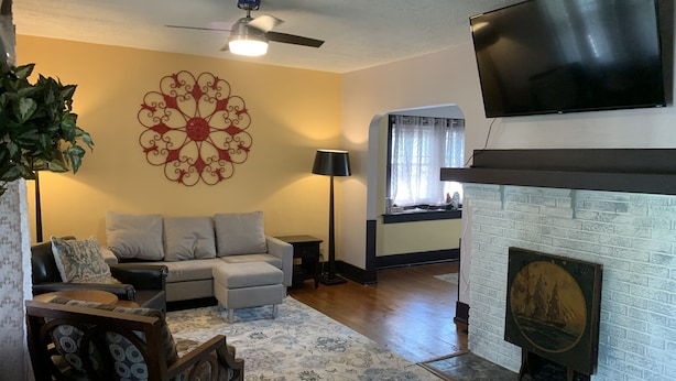 A living room with a sofa, a decorative wall piece, a fireplace, and a television mounted on the wall.