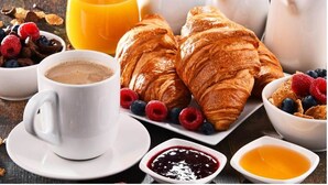 A breakfast setting with croissants, berries, coffee, and juice. - Dutch House (Amsterdam)