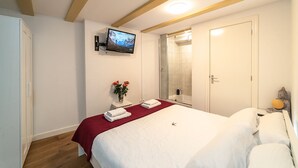 A hotel room with a bed, a TV mounted on the wall, a shower, and a door. - Dutch House (Amsterdam)