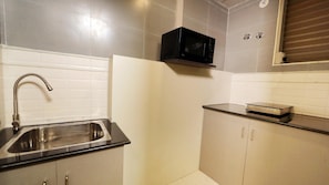 A kitchen with a stainless steel sink, a microwave, and a built-in oven. - The Zinc By The Fern (Bengaluru)