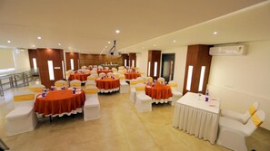 A conference room with multiple round tables, white chairs, and orange tablecloths. - The Zinc By The Fern (Bengaluru)