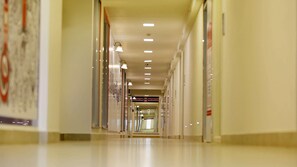 A corridor with overhead lighting, glass doors, and a sign indicating a price range. - The Zinc By The Fern (Bengaluru)