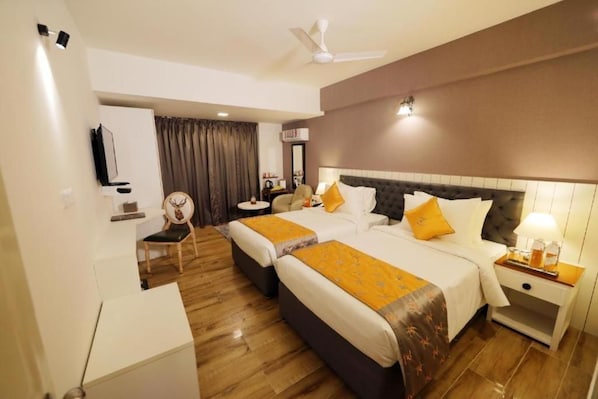 A hotel room with two beds, a ceiling fan, a TV, a desk, and a chair. - The Zinc By The Fern (Bengaluru)