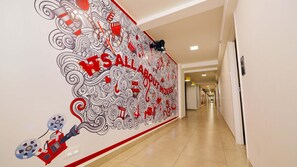 A hallway with a mural featuring movie-related graphics and the text 'WE ALL LOVE MOVIES'.