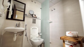 Baño con lavamanos, espejo, inodoro y ducha.